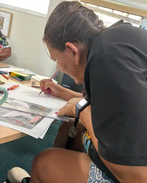 An NDIS participant concentrating on a drawing during a group art activity