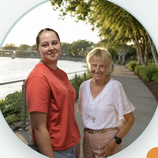 A member of the Transformative Nursing team with a smiling older client on a riverside walk